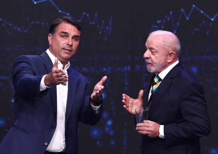 Dois homens conversando em palco, um dele flávio